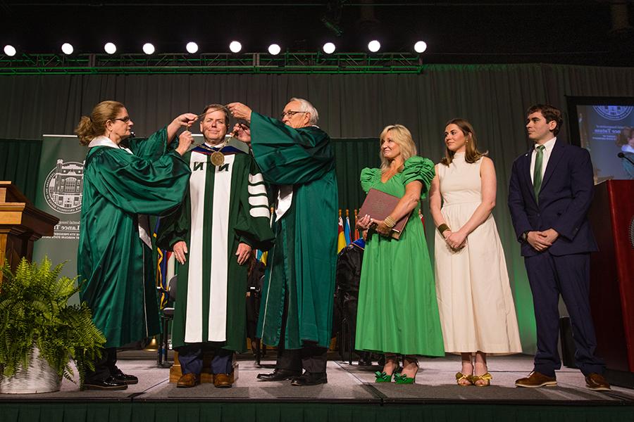 Northwest Regents Mel Tjeerdsma 和 Roxanna Swaney placed the University's chain of office on Dr. 兰斯·塔图姆的肩膀，他的家人在一旁看着. (Photo by Lauren Adams/<a href='http://rdiqpg.wolaipei.com'>网上赌博网站十大排行</a>)